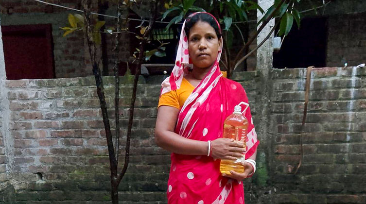 Eine Frau mit roter Kleidung hält eine Flasche in den Händen und schaut traurig