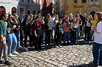 Eine Jugendgruppe steht im Halbkreis auf einem Markt