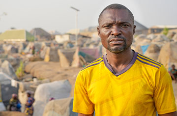 Porträt eines afrikanisch aussehenden Mannes vor einem Zeltlager