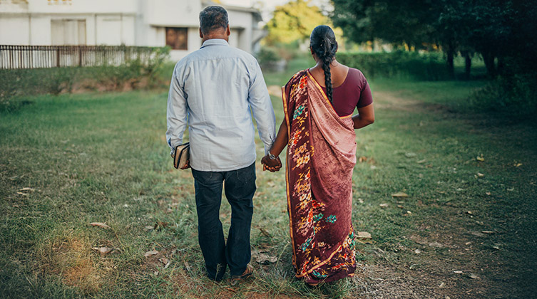 Ein Mann und eine Frau gehen Hand in Hand über eine Wiese