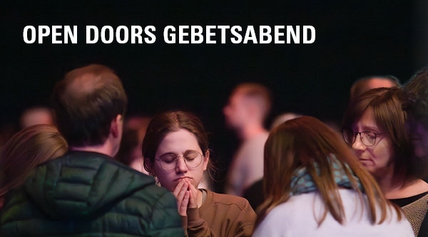 Menschen stehen gemeinsam betend in einer Halle