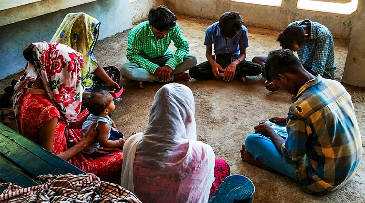 Indische Personene sitzten im Kreis auf dem Boden