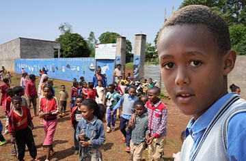 Portrait eines dunkelhäutigen Jungen mit blauem Poloshirt und im Hintergrund Schüler