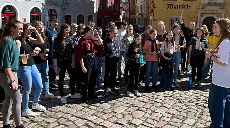 Eine Jugendgruppe steht im Halbkreis auf einem Markt