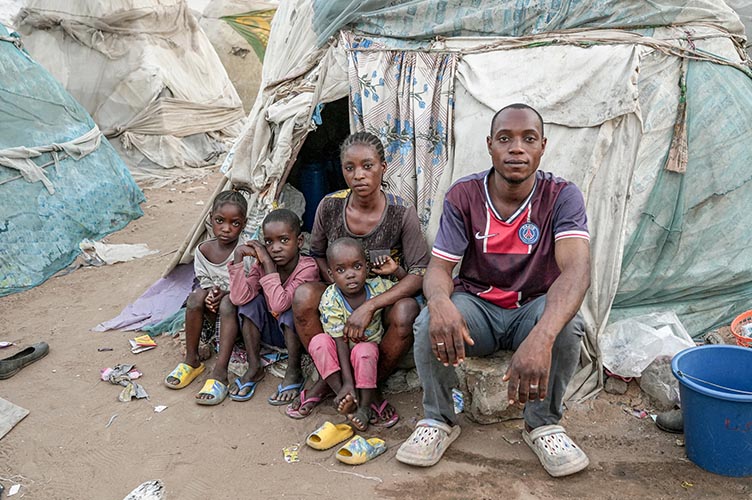 Eine geflüchtete Familie sitzt vor ihrem Zelt in der Flüchtlingsunterkunft.