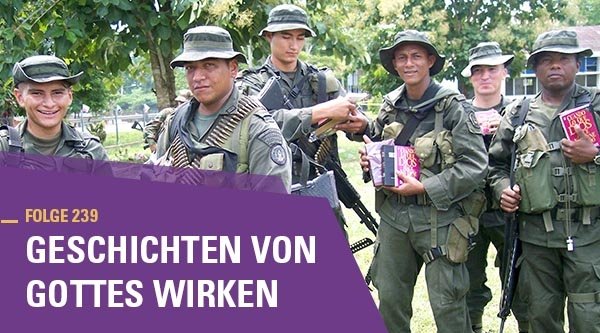 Junge Männer in grüner Tarnkleidung und militärischer Ausrüstung halten lächelnd Bibeln in ihren Händen